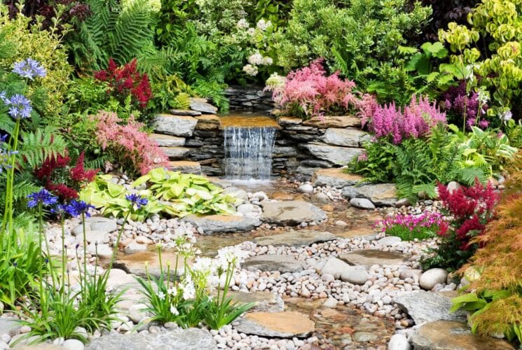 A rock and flower garden with water trickling over rocks into a small pool