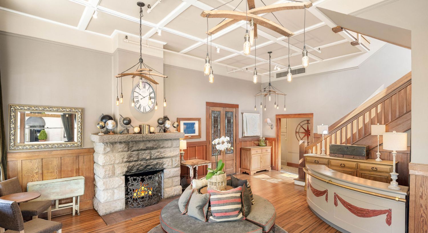 Bright and elegant front room of a home with fireplace, round bench seat, reception counter, hanging lights