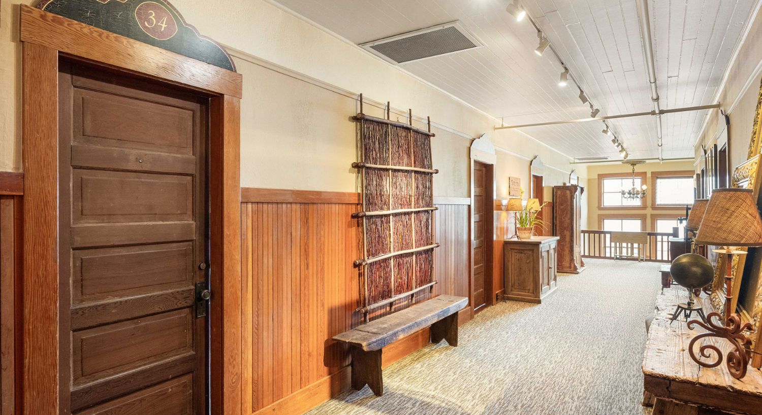 An upper level hallway showing several wood door each leading to a hotel room