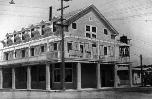 A historic black and white photograph of a three story hotel