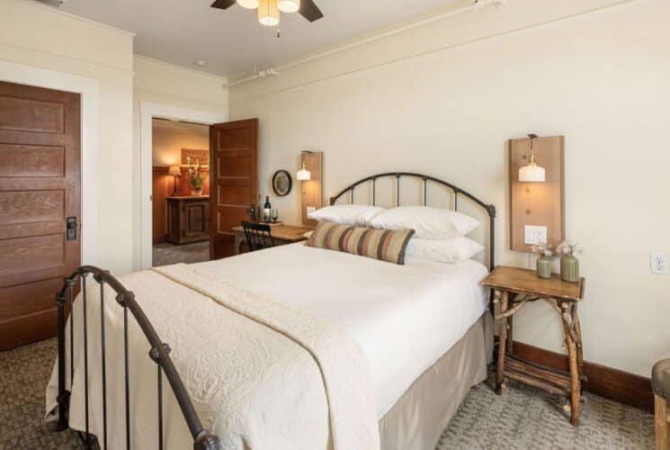 Bedroom with bed, curved headboard and footboard, side tables with lamps, two wood doors