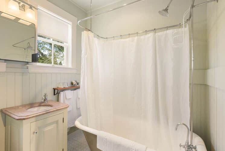 Bathroom with clawfoot tub, sink, mirror and windows with white shades